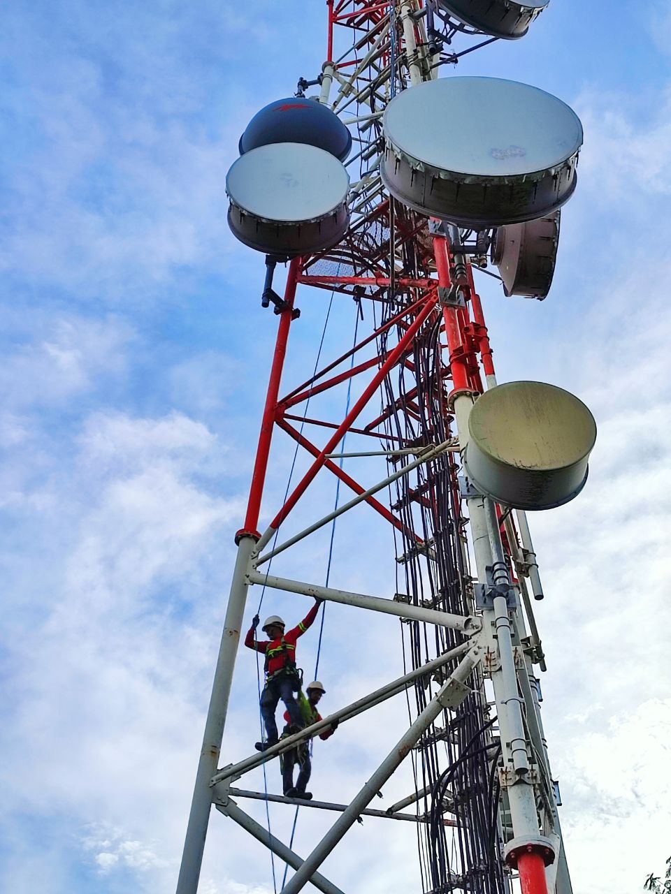 Field technician commissioning a microwave radio on a rooftop tower